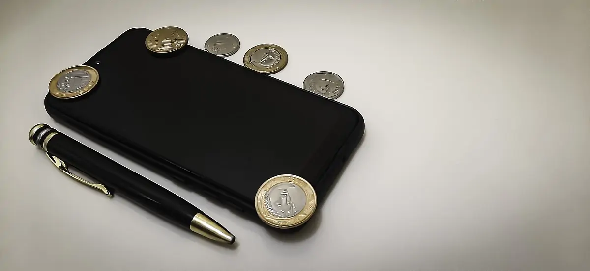 Mobile phone, money and pen on neutral background with copy space