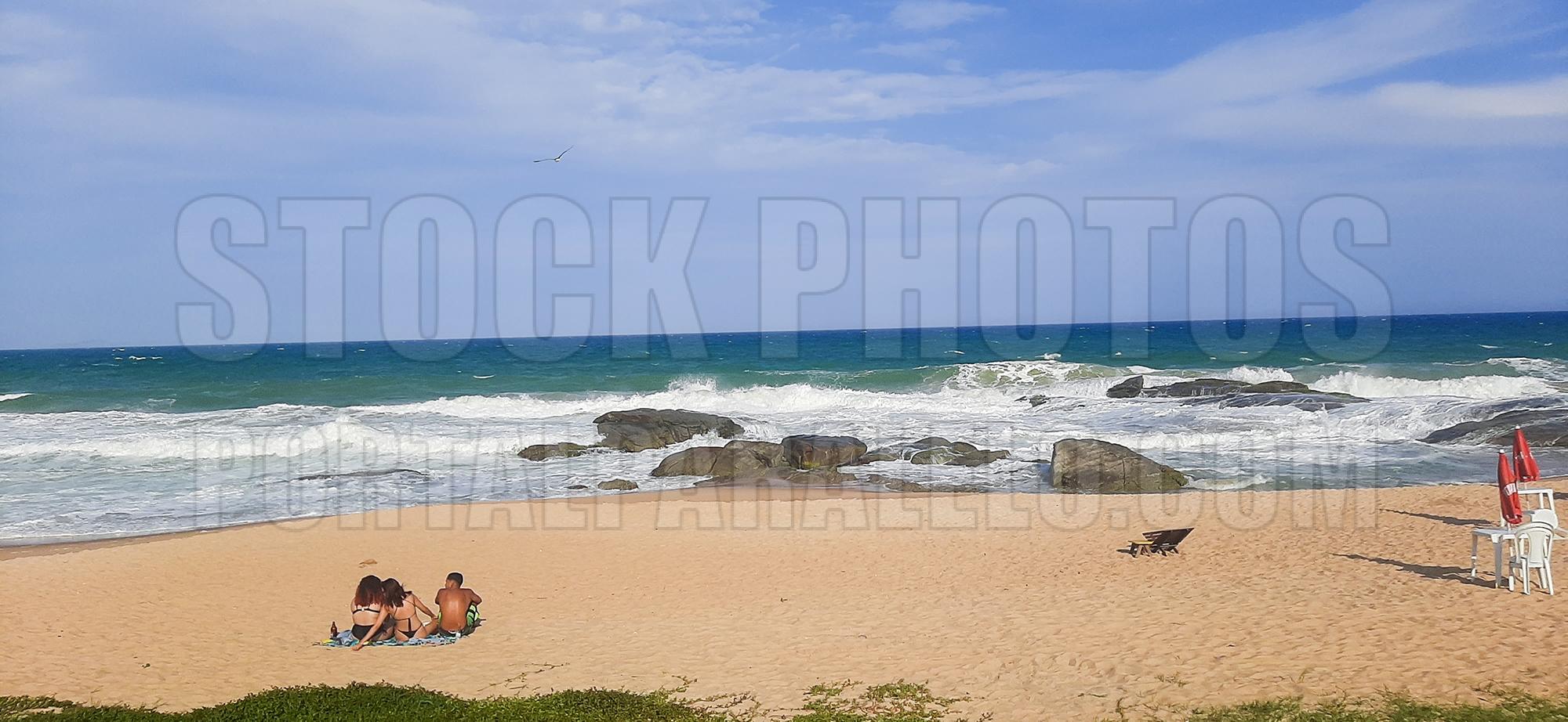 Three young people sitting on the beach admiring the sea