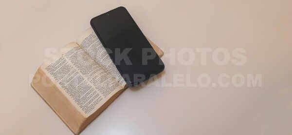 Mobile phone and holy bible on neutral background with copy space